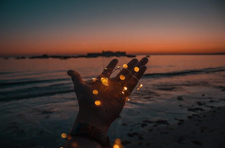 Une main entourée de lumière, tendue vers la mer
